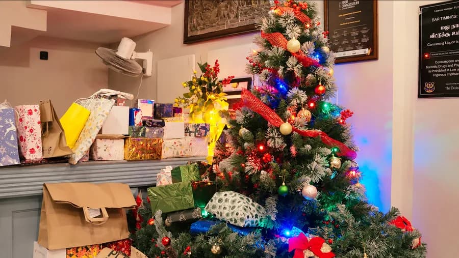 The office Christmas tree, lit, with the gifts piled beside it