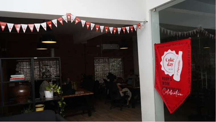 The office dressed for Coke day, bunting across the ceiling and the red banner by the glass